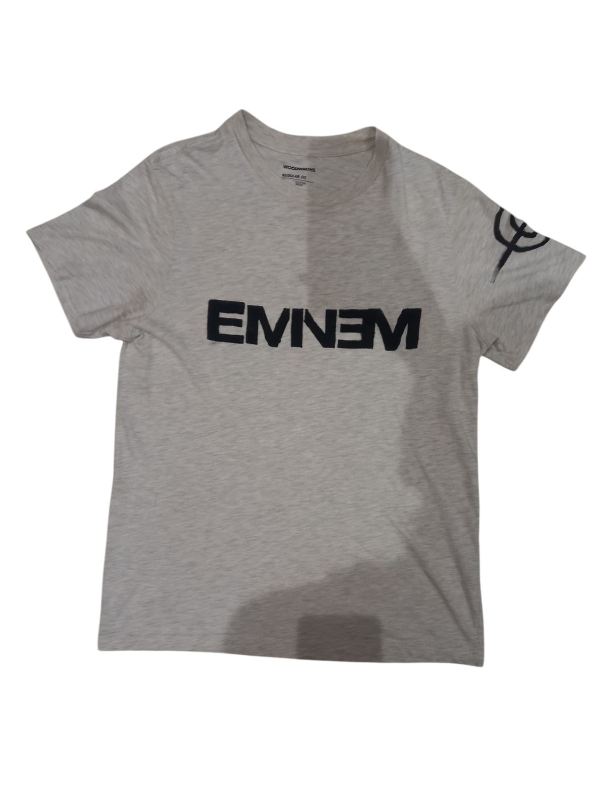 Light grey T-shirt with bold hand-painted black lettering and a sleeve mark
